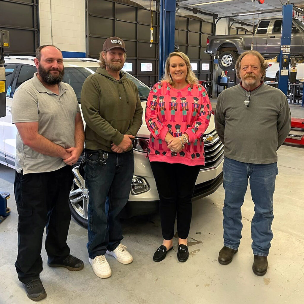 Three representatives of VGCC's faculty and staff stand with Dallas Herring nominee Kyle Harris in an automotive workshop