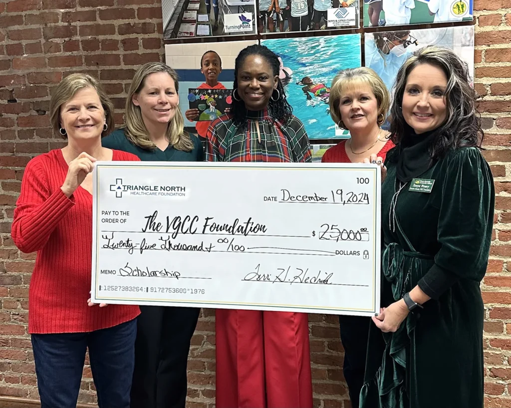 Five women pose with a large presentation check